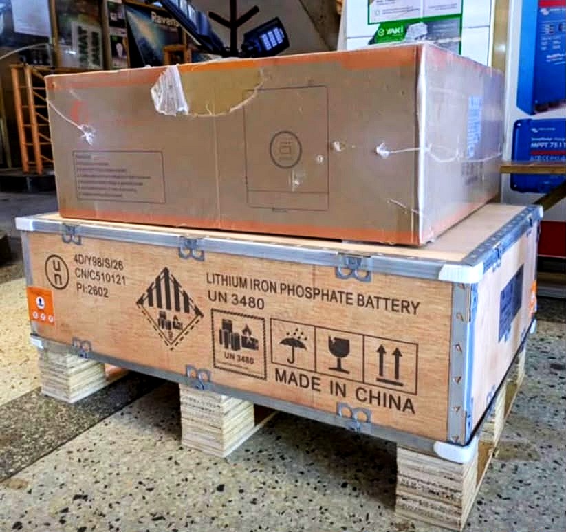 A wooden crate marked lithium iron phosphate battery with an inverter box on top