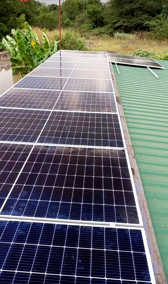 Solar panels mounted in a long line along a green iron sheet roof